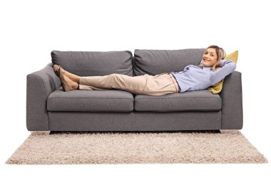 Genç bir kadın beyaz arka planda izole bir kanepede yatıyor.