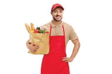 Üniformalı bir adam beyaz arka planda izole edilmiş yiyecek dolu bir kesekağıdı tutuyor.