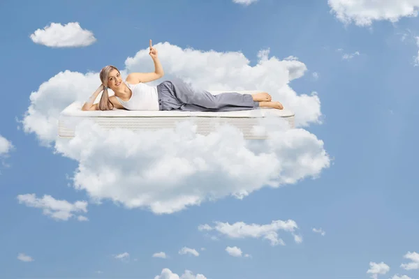 Young Woman Lying Comfortbale Mattress Pajamas Pointing Floating Clouds Sky — Stock Photo, Image