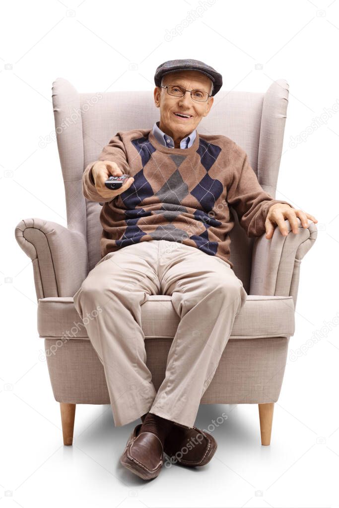 Full length portrait of a senior man sitting in an armchair and using a tv remote control isolated on white background