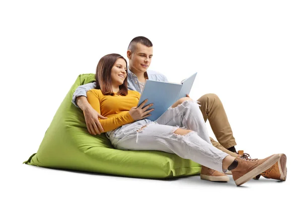 若い男と女学生座っています上の豆袋と読書A本孤立した白の背景 — ストック写真