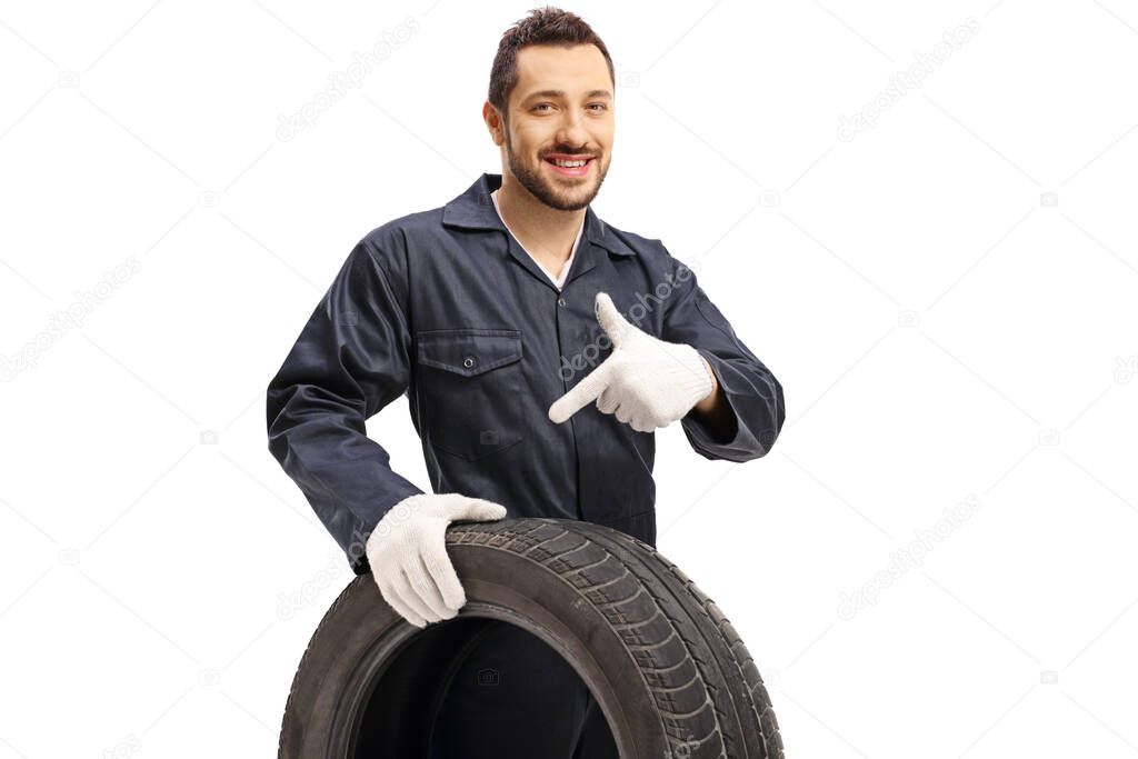 Auto mechanic holding a tire and pointing isolated on white background
