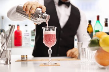 Barmen barda bardağa kokteyl dolduruyor.