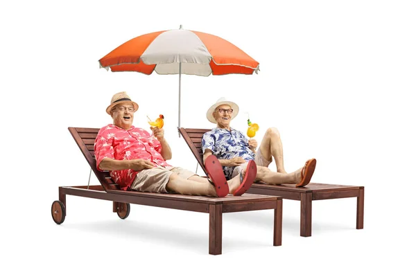 两名带着鸡尾酒的资深男性游客躺在日光浴床上 带着一把白色背景的雨伞 — 图库照片