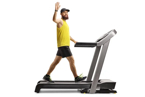 一个留着胡子的男子穿着运动服在跑步机上行走 在白色背景下挥动着双手的全景照片 — 图库照片