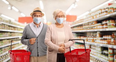Yaşlı çift süpermarkette alışveriş yapıyor ve tıbbi maske takıyor. 
