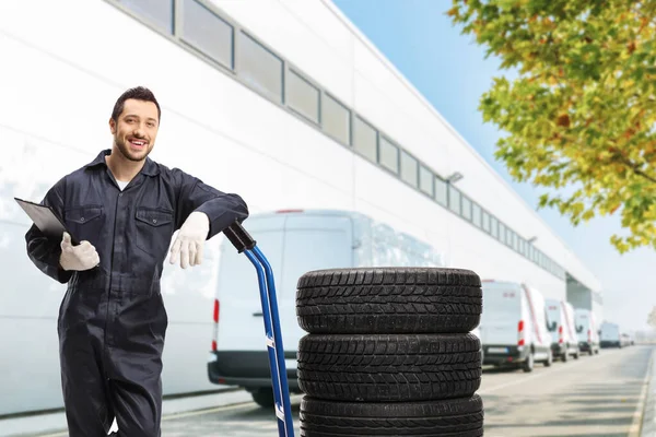 Männlicher Arbeiter Uniform Steht Mit Reifen Auf Einem Handwagen Vor — Stockfoto