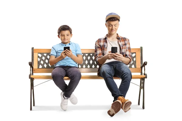 男性の子供と10代の若者がベンチに座って白い背景に隔離されたスマートフォンを見て — ストック写真