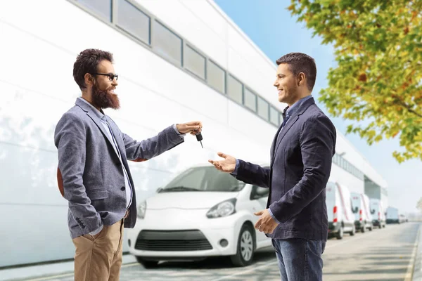 Bärtiger Mann Übergibt Autoschlüssel Eine Verkäuferin Vor Einem Auto Servicegebäude — Stockfoto