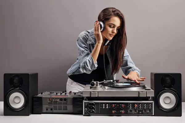 Young woman dj playing music on a gray background
