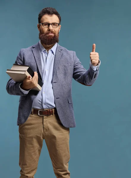 Bearded Male Teacher Holding Books Gesturing Thumb Sign Isolated Blue — Stock Photo, Image