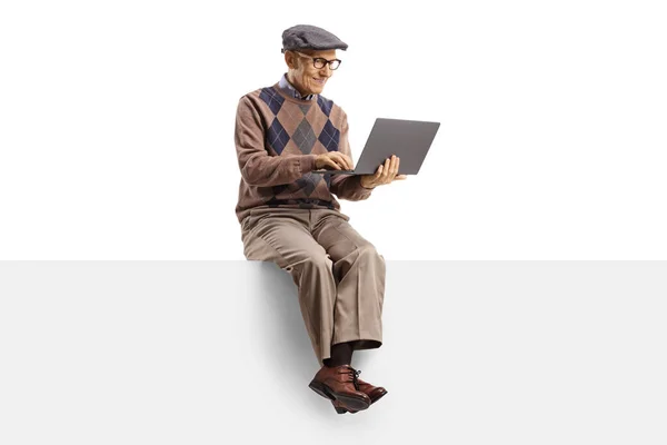 幸せな高齢者の男性は 空白のパネルに座って 白い背景に隔離されたラップトップコンピュータで作業します — ストック写真