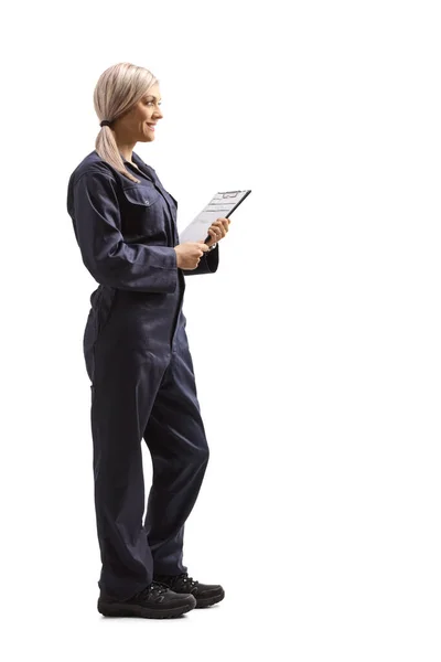 白い背景に隔離された文書とクリップボードを保持全体的な制服を着た女性労働者の完全な長さプロファイルショット — ストック写真