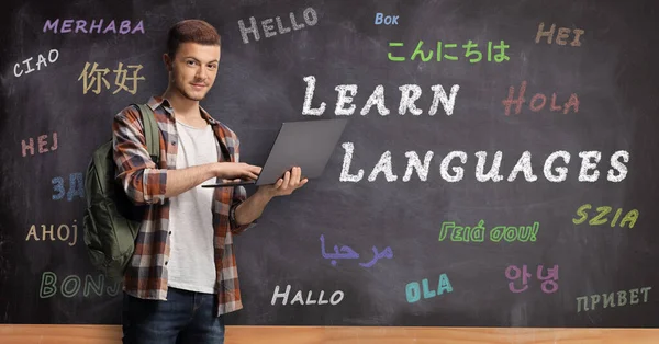 Mannelijke Student Met Laptop Voor Een Schoolbord Met Tekst Talen — Stockfoto