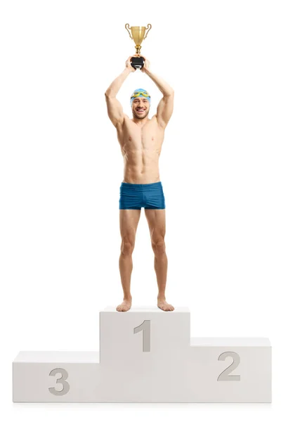 白い背景に隔離された勝者の表彰台に金のトロフィーカップを持ち上げる男性水泳の完全な長さの肖像画 — ストック写真