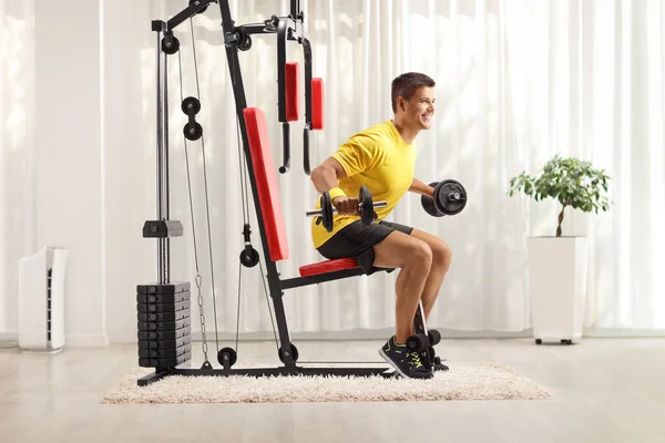 Fiatalember Gyakorolja Súlyzókat Egy Fitneszgépen Otthon — Stock Fotó