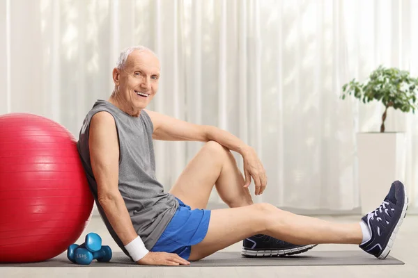 Starszy Mężczyzna Piłką Fitness Hantlami Siedzący Macie Treningowej Domu — Zdjęcie stockowe