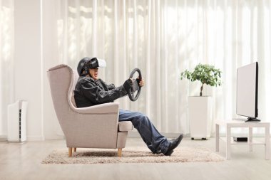 VR kulaklık takan ve televizyonun önünde direksiyon tutan yaşlı bir adam. 