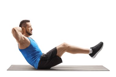 Beyaz arka planda izole edilmiş bir paspas üzerinde karın kasları çalıştıran zinde genç bir adam.