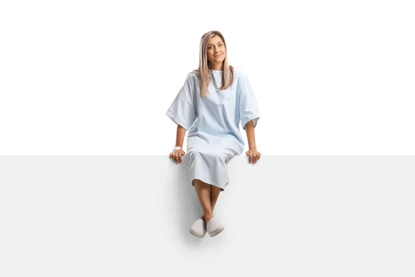 Vrouwelijke Patiënt Een Ziekenhuisjurk Zittend Een Blanco Paneel Geïsoleerd Witte — Stockfoto