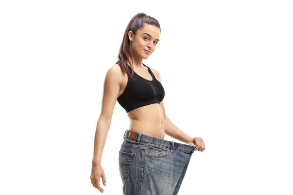 若いですスリム女性身に着けています大きなサイズのペアのジーンズ後に重量損失隔離された白の背景 — ストック写真
