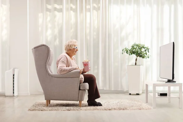 Starsza Kobieta Okularach Siedzi Fotelu Ogląda Telewizję Domu — Zdjęcie stockowe