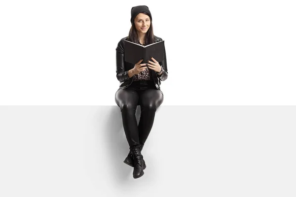 Ung Kvinna Läder Kläder Sitter Tom Panel Med Bok Isolerad — Stockfoto