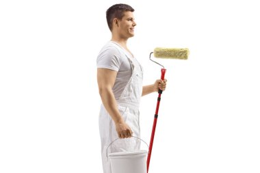 Beyaz arka planda bir kova ve bir boya silindiri tutan ressam.