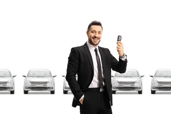 Autoverkäufer Mit Autoschlüssel Vor Einer Reihe Silberner Autos Auf Weißem — Stockfoto