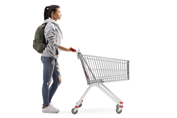 白い背景に隔離された空のショッピングカートを持つ女性学生の完全な長さのプロフィールショット — ストック写真