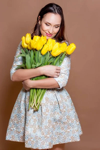 Giovane bella donna che tiene un mazzo di tulipani gialli. Primavera . — Foto Stock