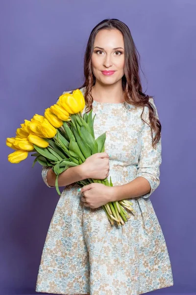 Giovane bella donna che tiene un mazzo di tulipani gialli. Primavera . — Foto Stock