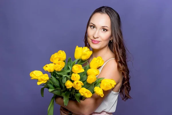 Ung vacker kvinna som håller en bukett med gula tulpaner. Våren. — Stockfoto