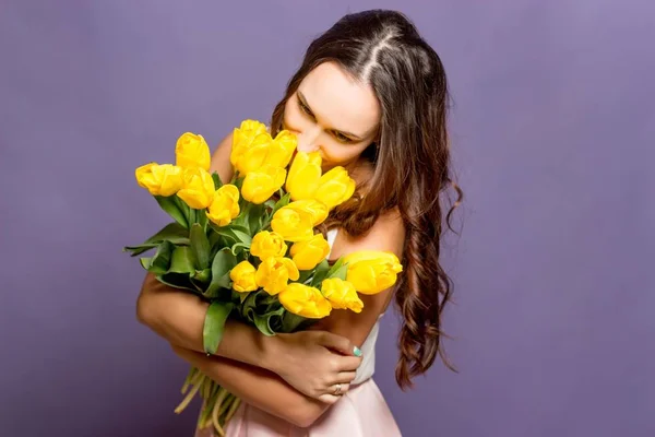 年轻漂亮的女人抱着一束黄色郁金香。春天. — 图库照片