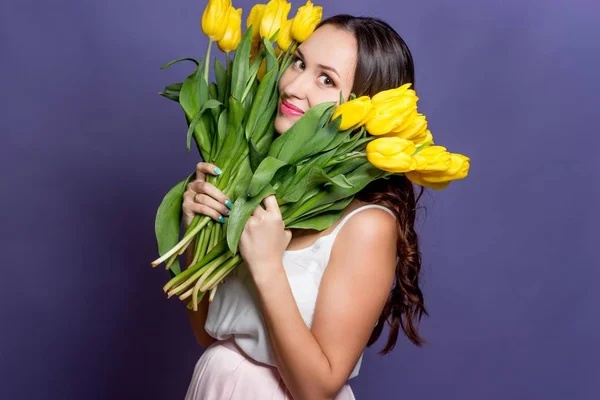 Ung vacker kvinna som håller en bukett med gula tulpaner. Våren. — Stockfoto