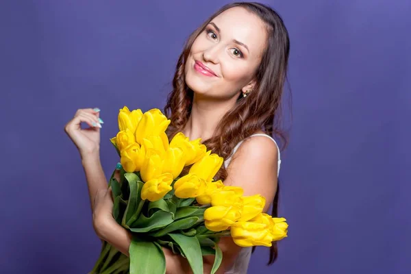 Jovem mulher bonita segurando um buquê de tulipas amarelas. Primavera . — Fotografia de Stock