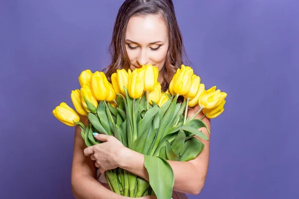 Jovem mulher bonita segurando um buquê de tulipas amarelas. Primavera . — Fotografia de Stock