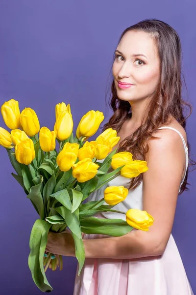 Ung vacker kvinna som håller en bukett med gula tulpaner. Våren. — Stockfoto