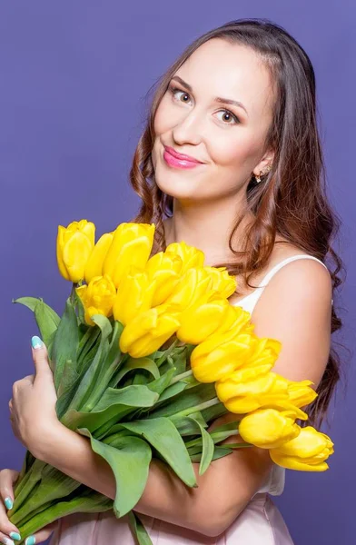 Jovem mulher bonita segurando um buquê de tulipas amarelas. Primavera . — Fotografia de Stock