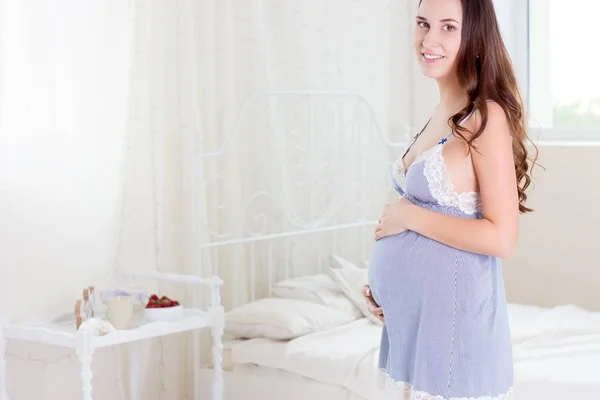 Hamile bir kadın yatak odasında duruyor. Hamile kadın rahatlatıcı. — Stok fotoğraf