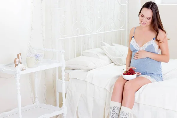 Donna incinta felice seduta sul letto. Una giovane donna incinta è seduta in camera da letto. Donna incinta rilassante. Giovane pregna — Foto Stock