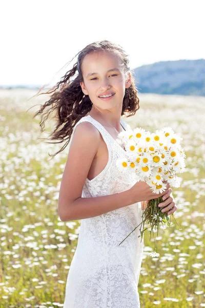 Happy girl walking in a field. Girl resting in a field of chamomile. Girl gathers daisies. Warm spring. — Stock Photo, Image