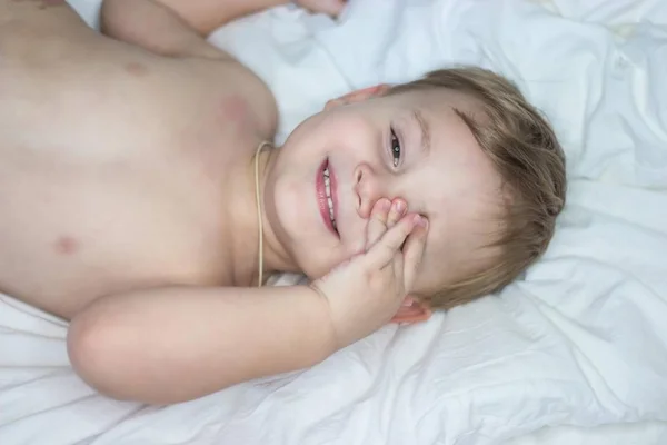 Портрет милого маленького счастливого мальчика. Младенец дурачится в постели . — стоковое фото