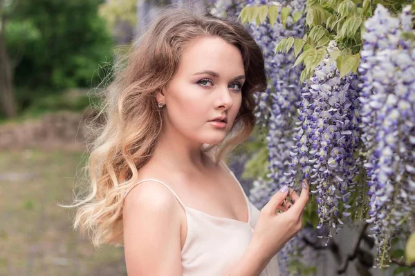 Wisteria. Portrait d'une jeune belle femme près de fleurs lilas. Printemps chaud . — Photo