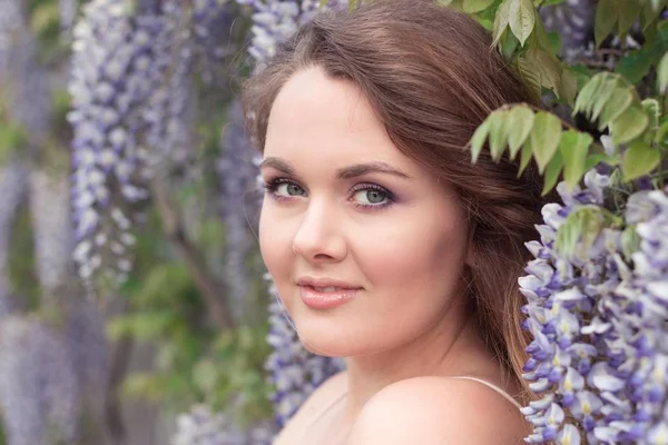 Wisteria. Portrait of a young beautiful woman near lilac flowers. Warm spring. — Stock Photo, Image