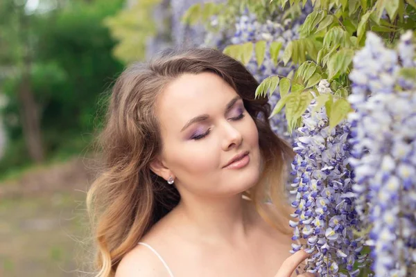 Wisteria. Eflatun çiçekler yakınındaki güzel bir genç kadının portresi. Sıcak bahar. — Stok fotoğraf