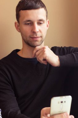 Genç bir adam portresi. Genç adam telefonla söyledi. Ofiste genç bir adam oturuyor.