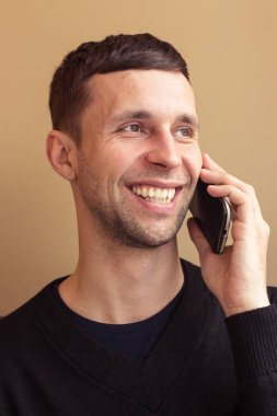 Genç bir adam portresi. Genç adam telefonla söyledi. Ofiste genç bir adam oturuyor.