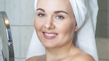 Başında beyaz bir havlu ile mutlu bir genç kadın. Sonra bir havlu duşta kız.