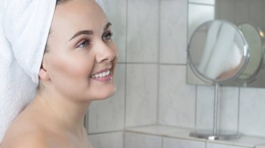 Başında beyaz bir havlu ile mutlu bir genç kadın. Sonra bir havlu duşta kız.